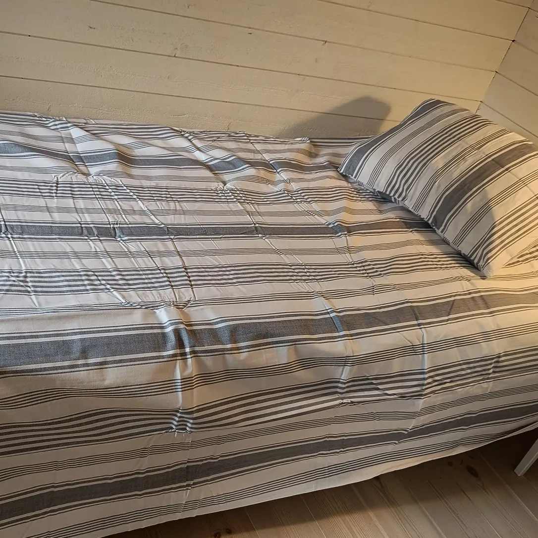 Bäddat med extra långt täcke i blårandigt bäddset